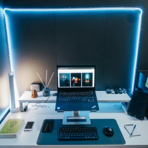 A modern home office desk setup with a laptop, books, and LED lighting for productivity.