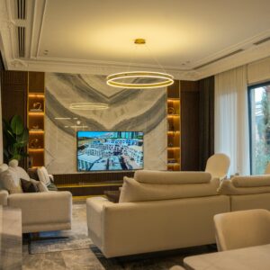 Luxurious contemporary living room showcasing modern furniture, lighting, and decor with large windows.