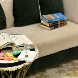 Elegant living room setup with a plush sofa, stack of books, and colorful stationery for a study vibe.