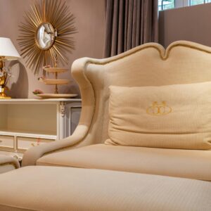Comfortable classic beige folding sofa bed with cushion placed at wall near cupboard with lamp and decorative elements in light room